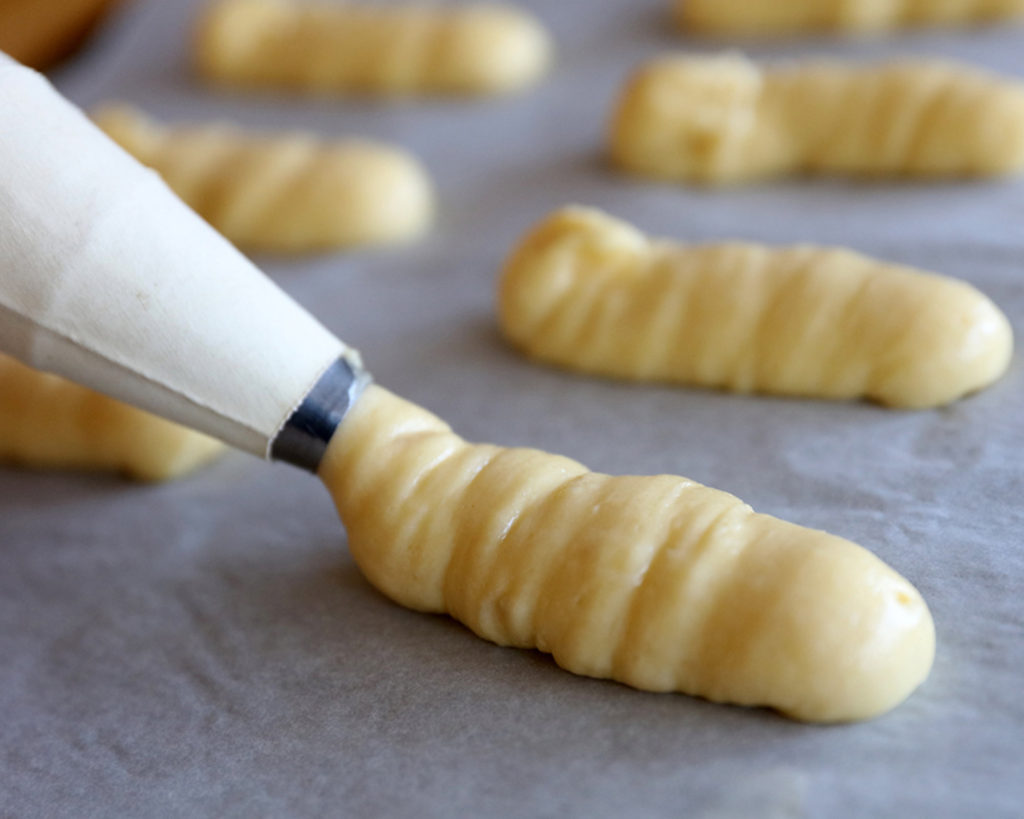 pipping the pate choux on to parchment paper.